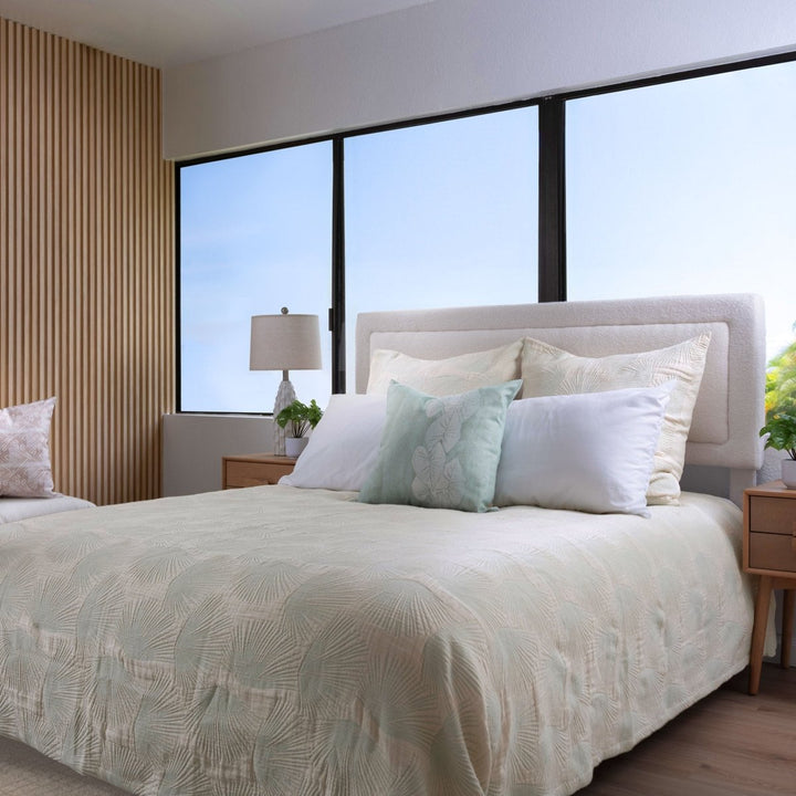 Loulu green coverlet on bed with fan palm pattern, styled with pillows and tropical greenery in a lush home setting.