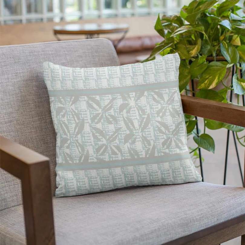image of light blue square pillow on chair with Hawaiian alphabet pattern