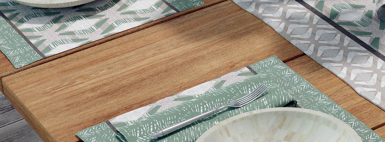 Coastal Placemats With Hawaiian Prints in Green Set on a Wood Dining Table With Plates and Utensils