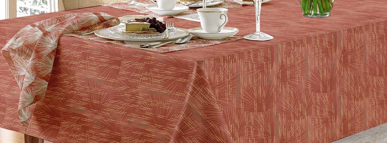 Coastal Tablecloths With Loulu Hawaiian Print Shown in Orange Color on a Large Dining Table With Crystal Glasses