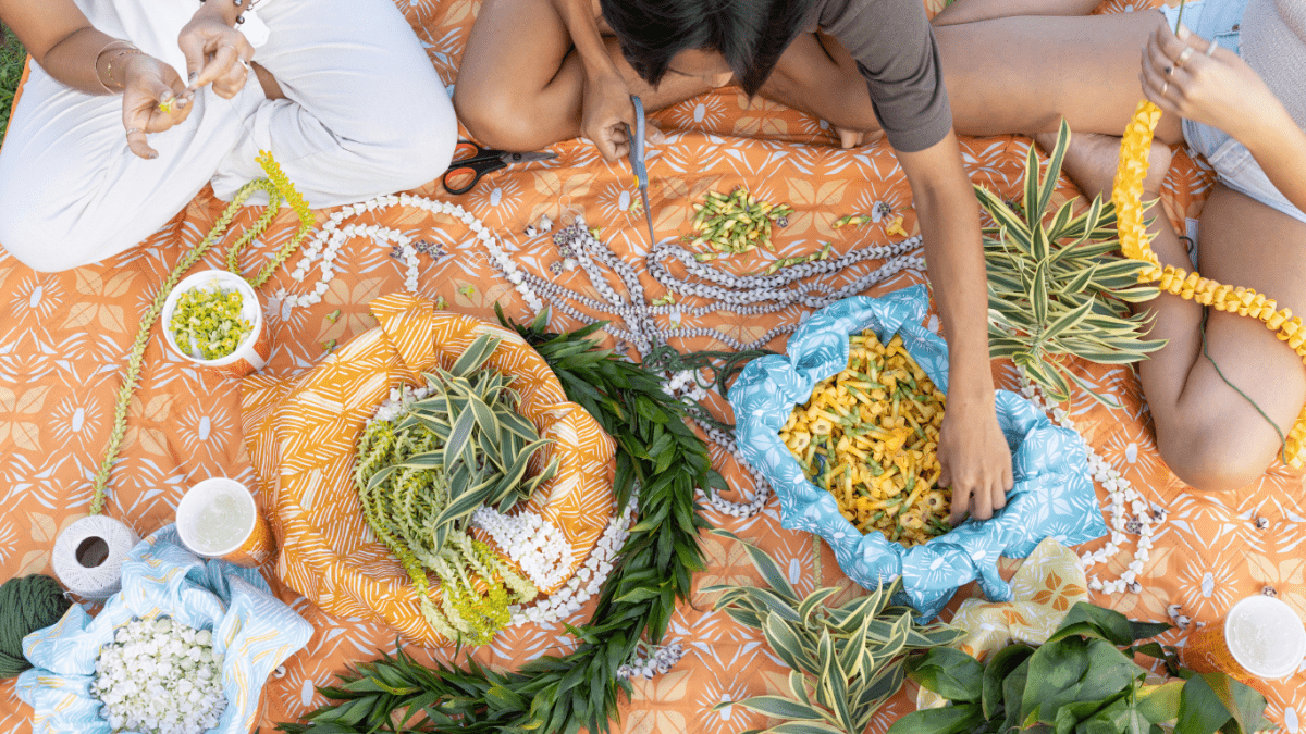 Hawaiian picnic blanket, flowers, lei, tea towels and they are making lei
