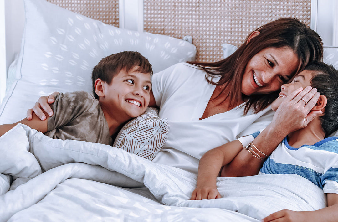Woman With Her Son and Daughter Laughing On a Bed