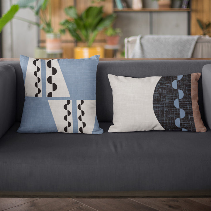 Black and Beige Tatau Kau Lumbar Pillow Set Next to a Tatau Kai Square Pillow On a Dark Grey Couch