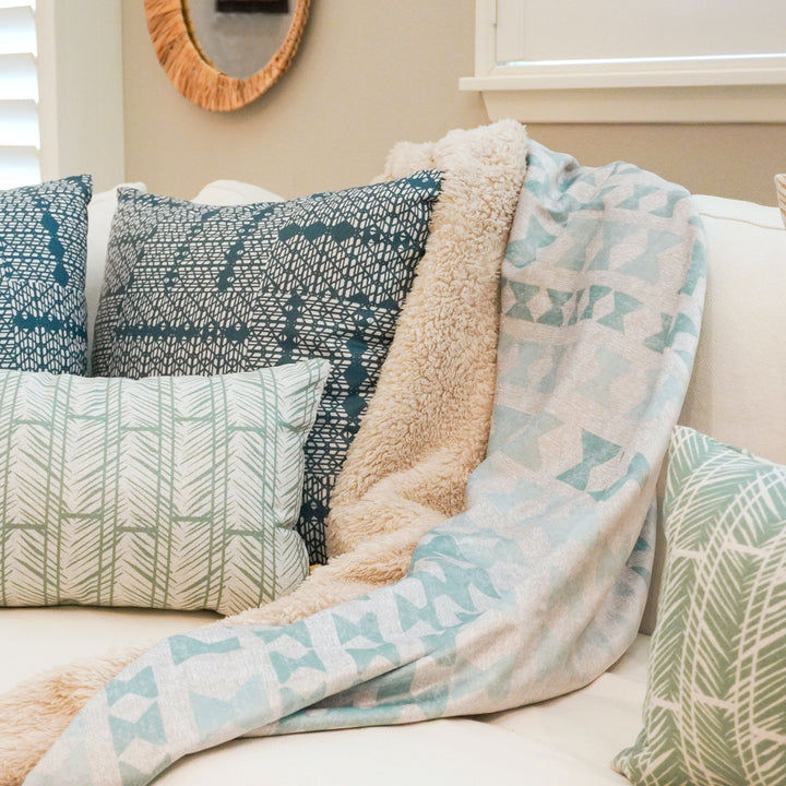 image of cozy throw next to pillows on couch