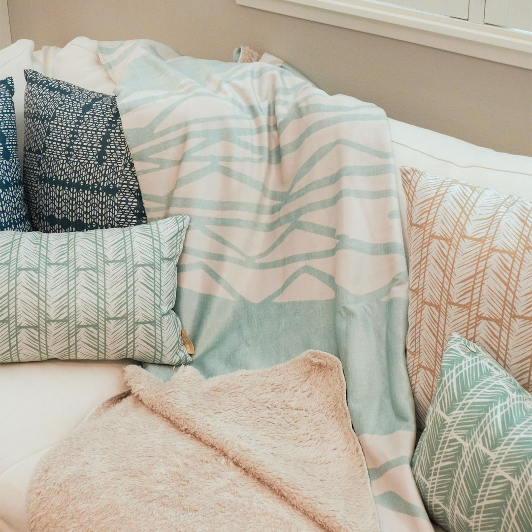 image of cozy throw next to pillows on couch