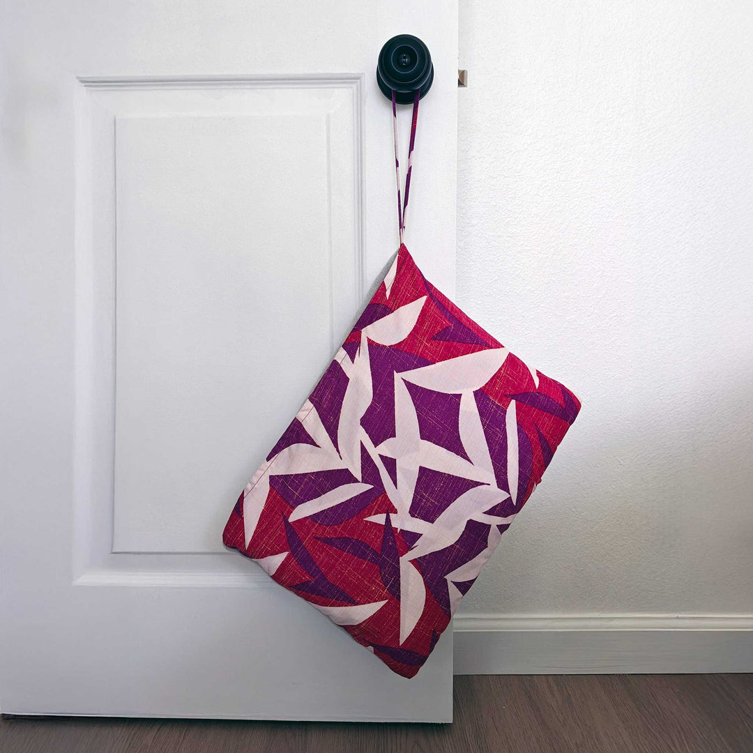 Hawaiian Airlines NOHO HOME travel blanket in pink hanging on door knob in lifestyle setting