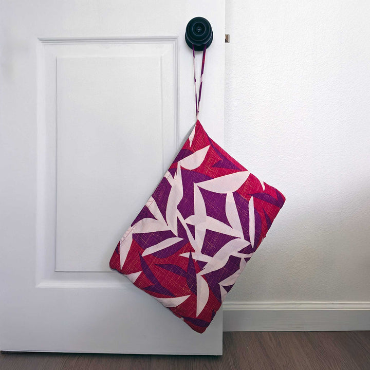 Hawaiian Airlines NOHO HOME travel blanket in pink hanging on door knob in lifestyle setting
