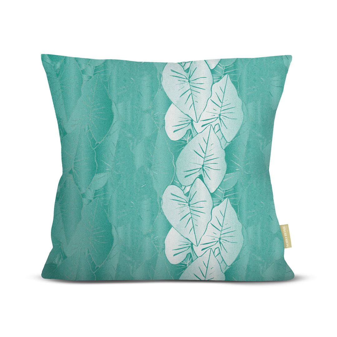 Teal pillow with white kalo leaf pattern on a white background.