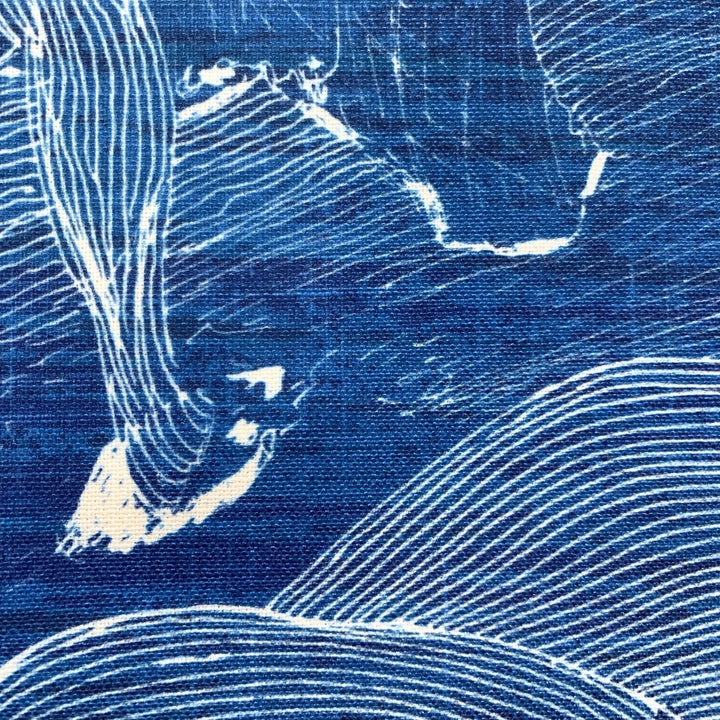 Close up detail of decorative pillow with abstract line art design of a fisherman on Molokaʻi with a blue background