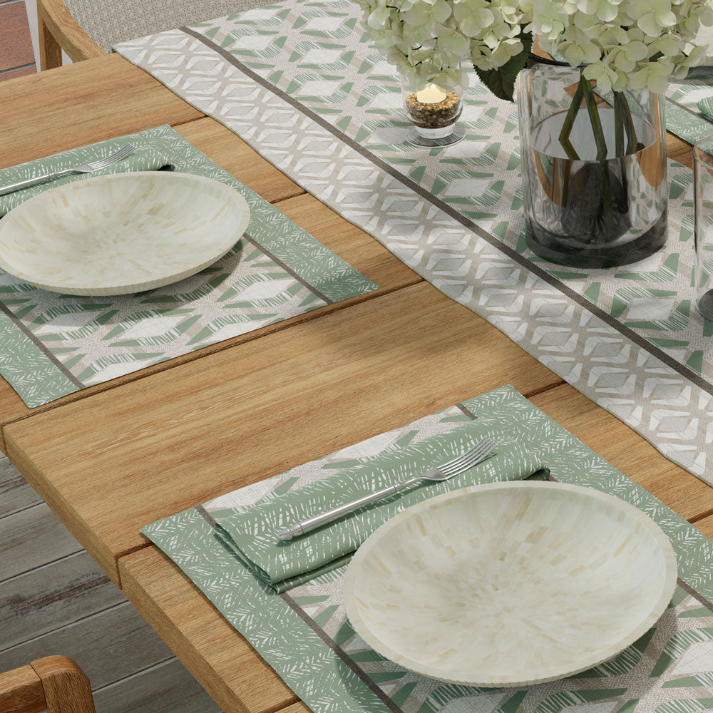 Seafoam Kāholo Placemat settings with Batik napkins, flatware and plate.  Kāholo table runner with floral arrangement and votive.