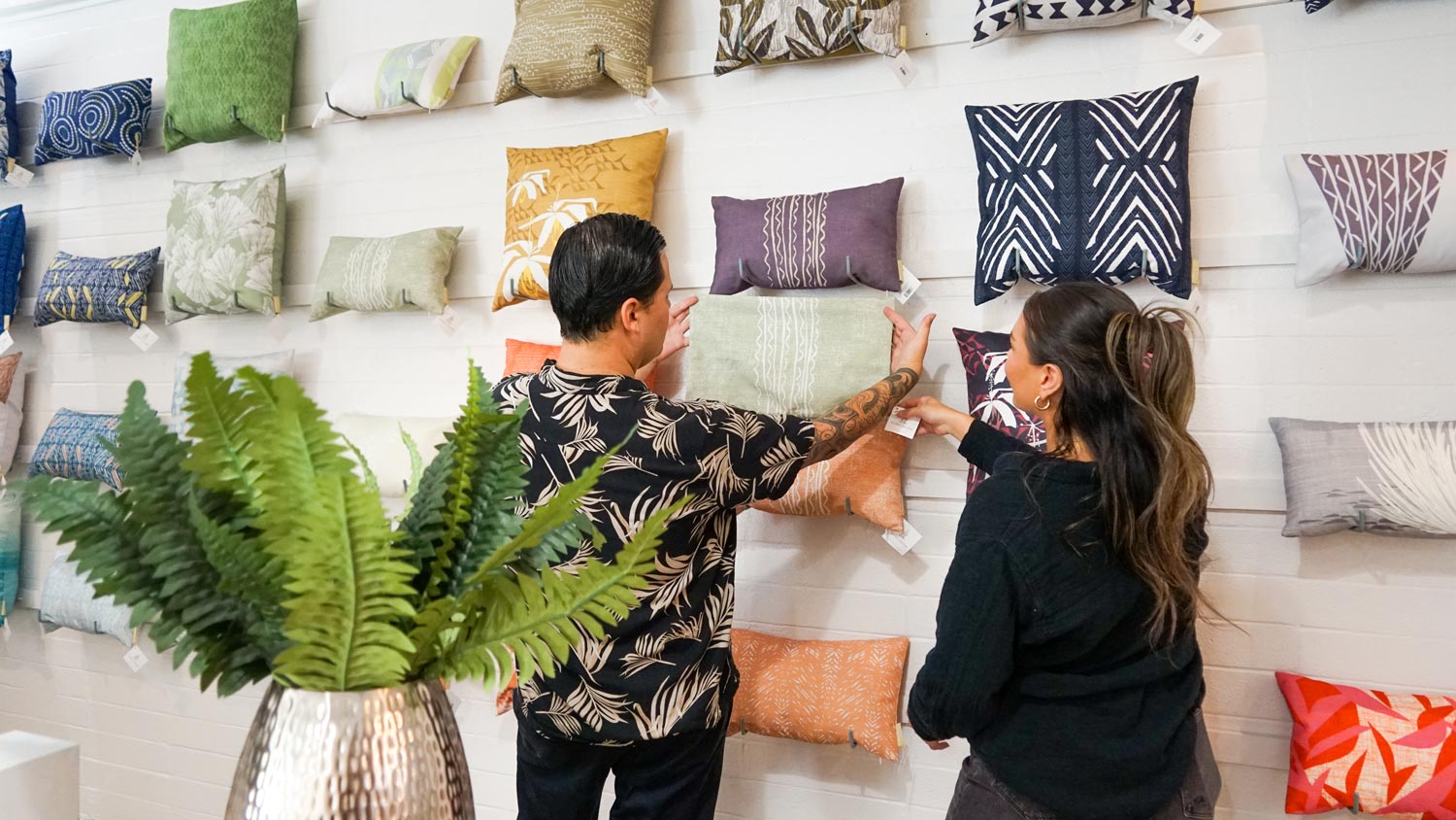 two people looking at pillows displayed on wall at NOHO HOME Honolulu retail store