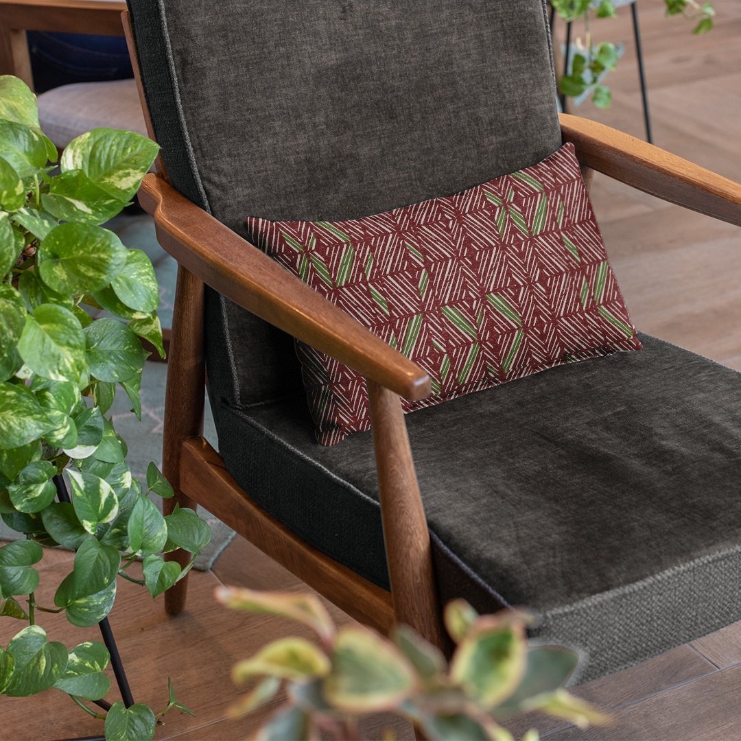 Pine & Cranberry 'Akahi Lumbar Pillowcase on a gray chair with a plant accent on the side