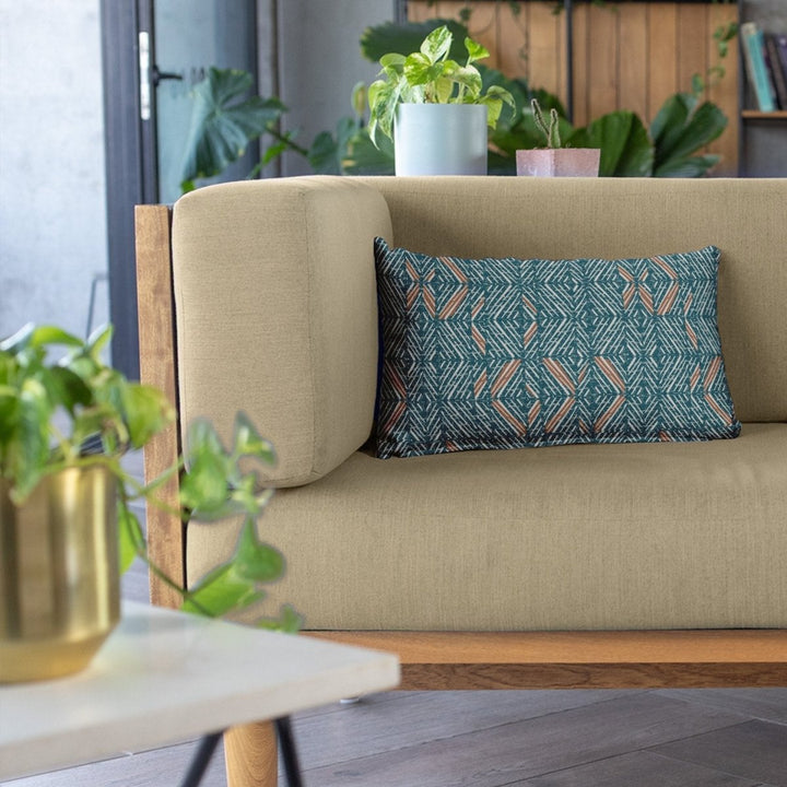 Cocoa & Aqua 'Akahi Lumbar Pillowcase resting on an olive sofa surrounded by plants in a lighted living area