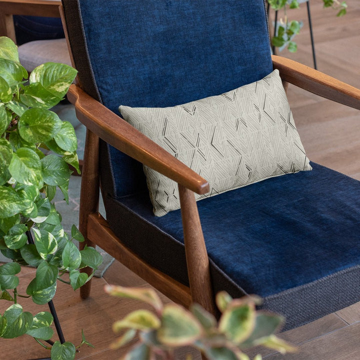 Taupe & Ivory 'Akahi Lumbar Pilowcase placed on a dark blue chair with plant accent on the side