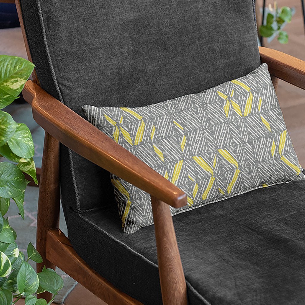 Illuminating & Ultimate Gray ʻAkahi Lumbar Pillowcase in a gray and wood chair with a plant accent on the side