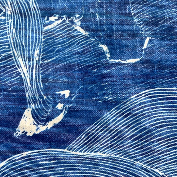 Close up detail of decorative pillow with abstract line art design of a fisherman on Molokaʻi with a blue background