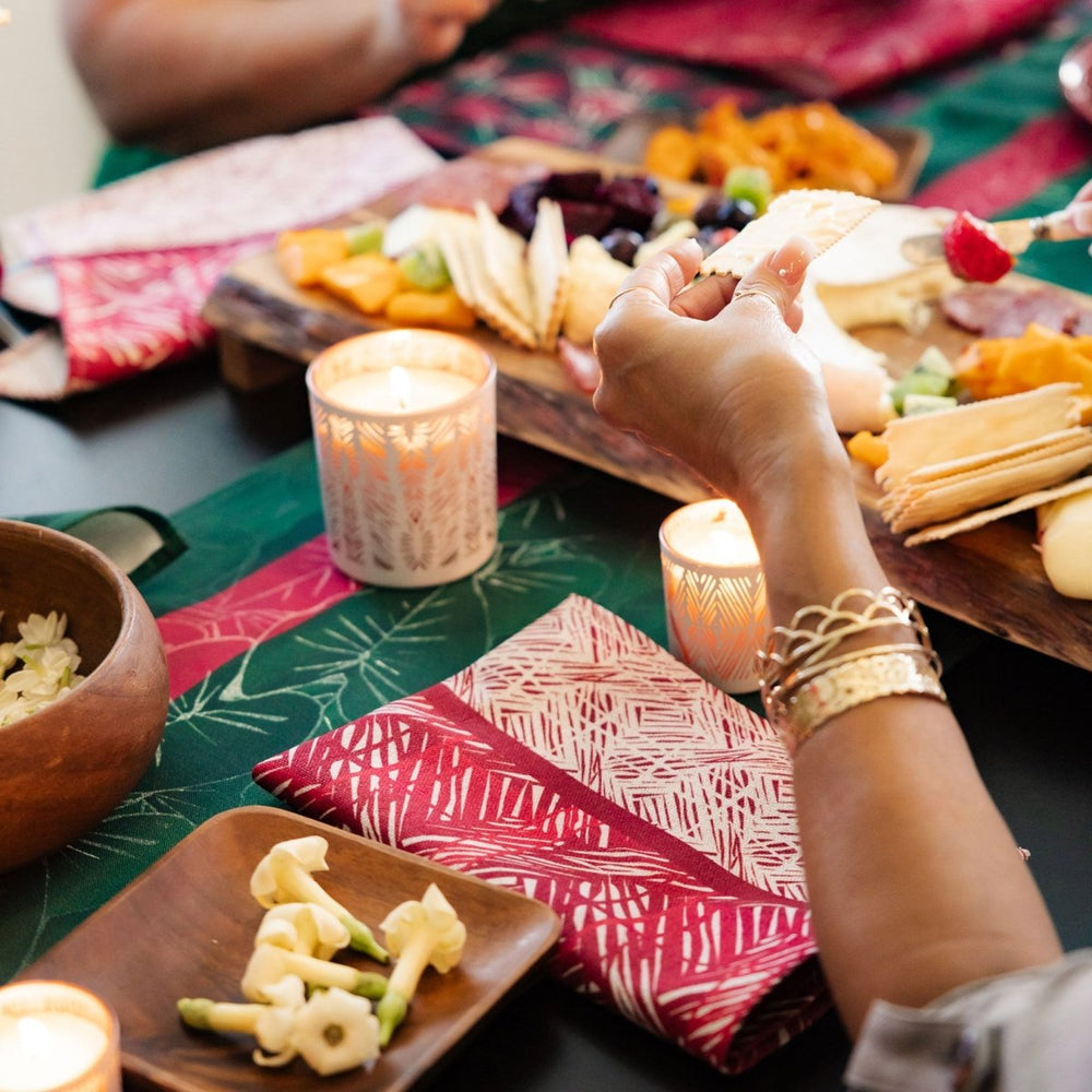 People enjoying a festive meal with candles and a colorful tablecloth.