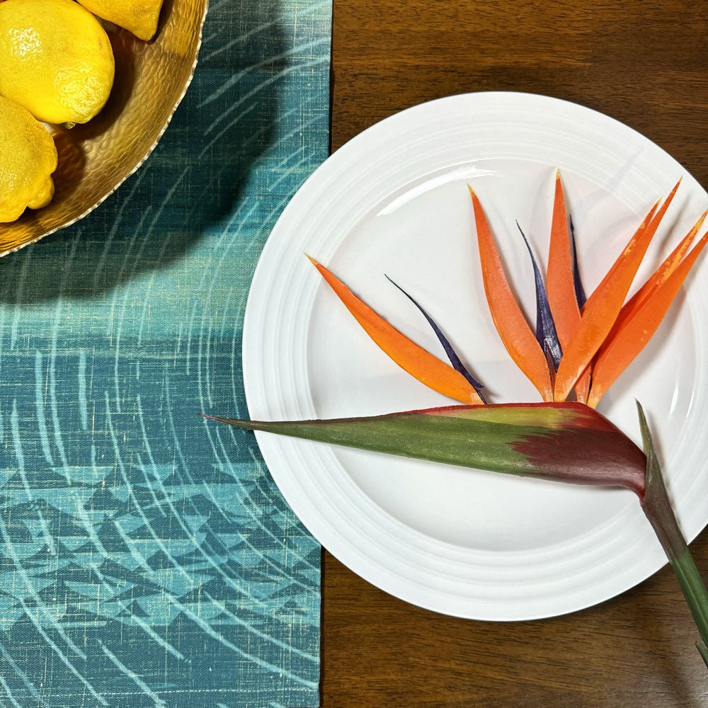 Kilo Hōkū Tea Towel Set Under a Small Plate With a Bird of Paradise On It