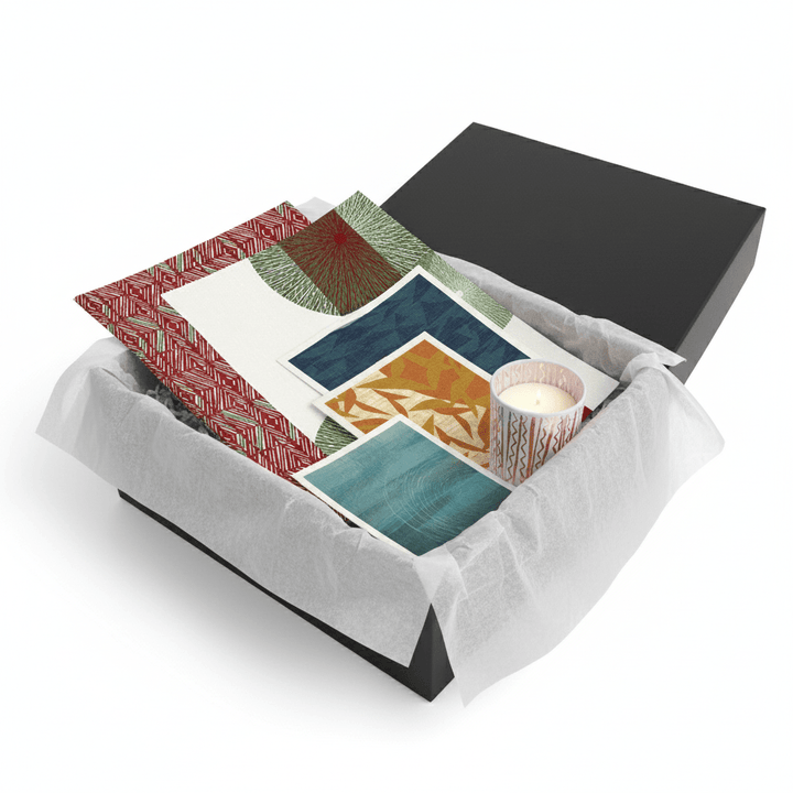 Gift set with a candle, tea towels and reusabale cloth in an open black box on a white background.