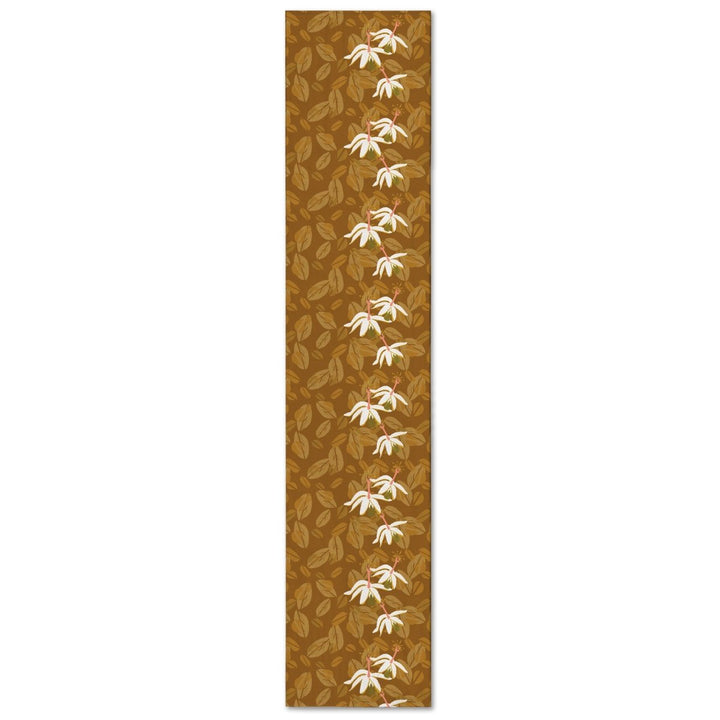 Caramel Kokiʻo Table Runner with cream blossoms down the center over tonal leaves, shown full length on a white background