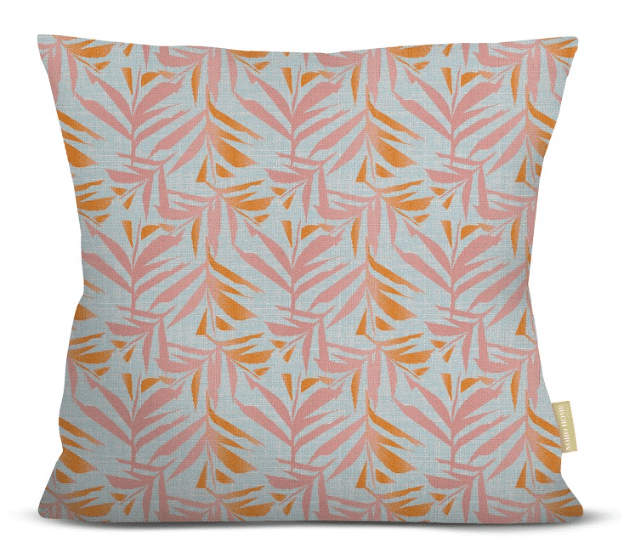 Decorative pillow with pink and orange leaf pattern on a light blue background