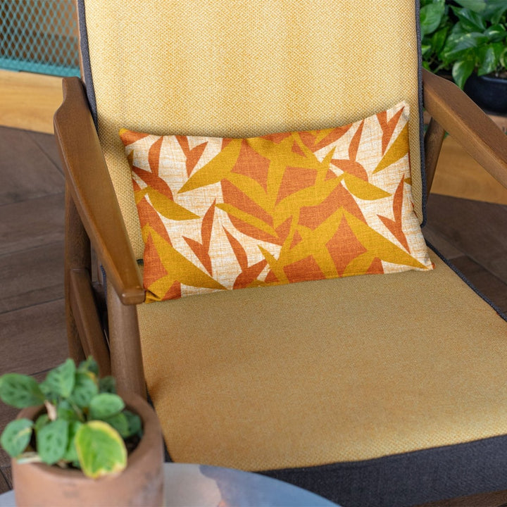 Sunset Lele Lumbar Pillowcase placed on a beige chair with plant on a side table