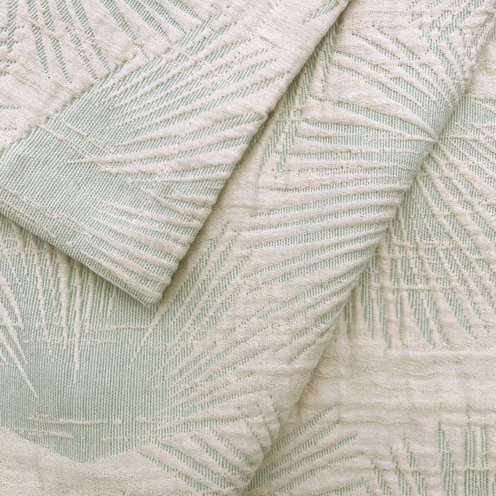 Textured fabric with a subtle fan palm leaf pattern in light green and beige.