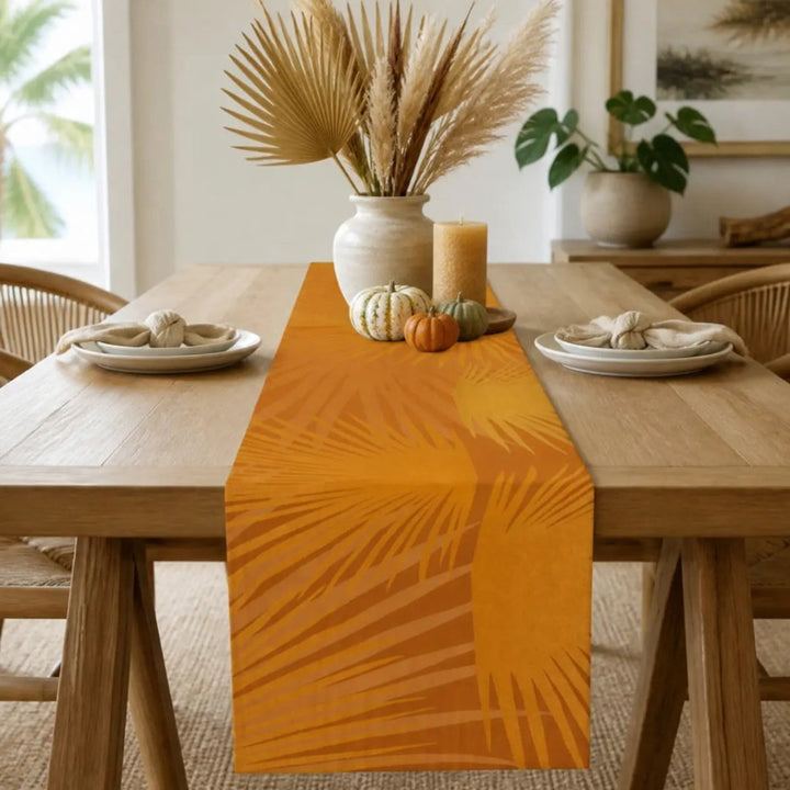 Pumpkin Loulu Palm Table Runner styled down an oak dining table with cream plates, mini pumpkins, a pillar candle and a vase of dried palm fronds