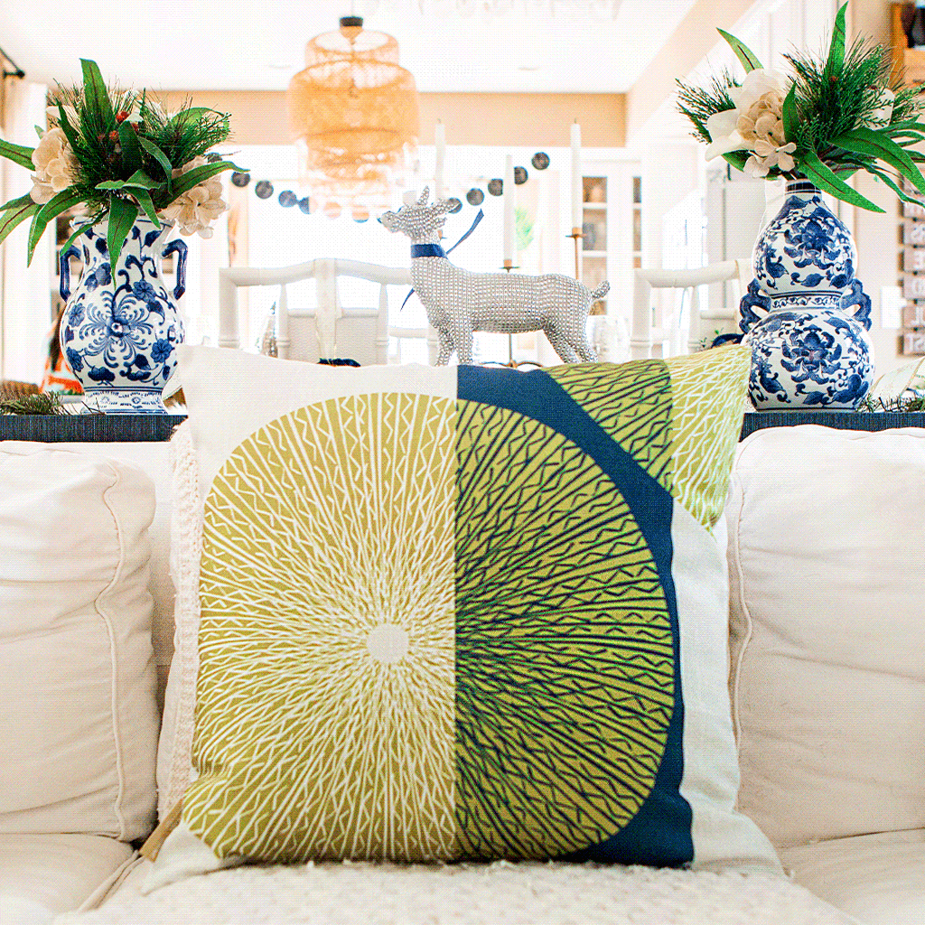 Moss & Navy Niho Medallion Square Pillow on an ivory sofa with China Blue pottery in back.