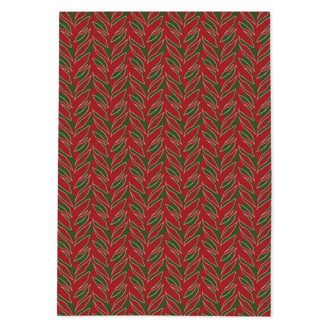 Kī tea towel laid flat: green ti leaves on holiday red