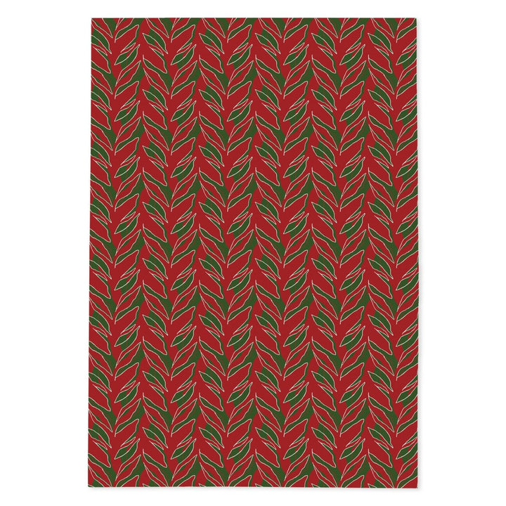 Kī tea towel laid flat: green ti leaves on holiday red