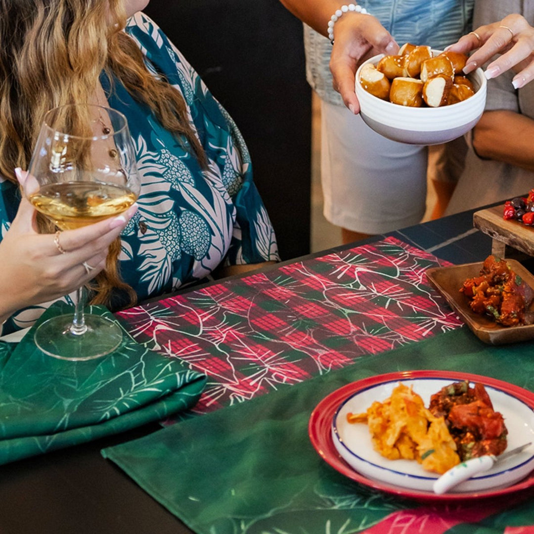 People enjoying a meal with wine and food on a table with christmas placemats.