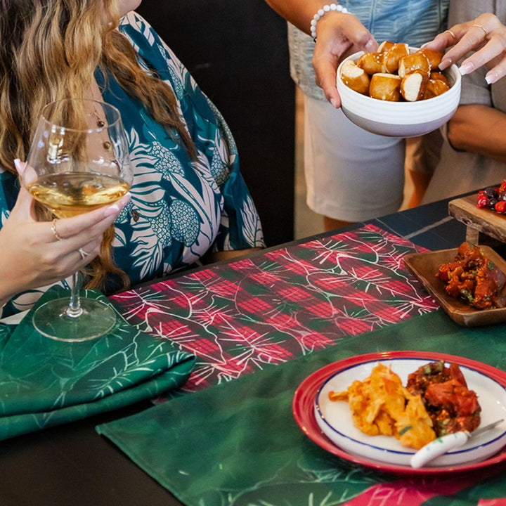 People enjoying a meal with wine and food on a table with christmas placemats.