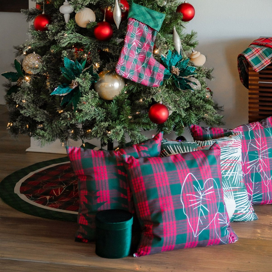 Christmas tree with plaid decorations and stockings, surrounded by Noho Home Pillow presents on a wooden floor.