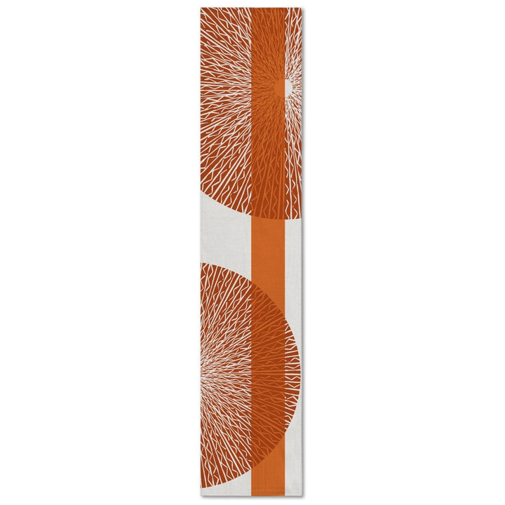 A rectangular table runner with a white background and an orange niho medallion pattern.