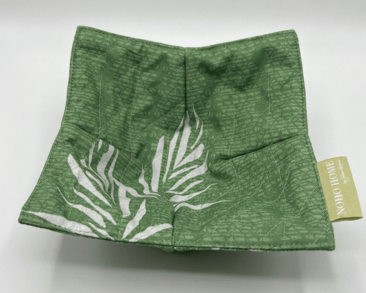 green bowl cozy square with white leaf pattern and a visible brand tag on a white background