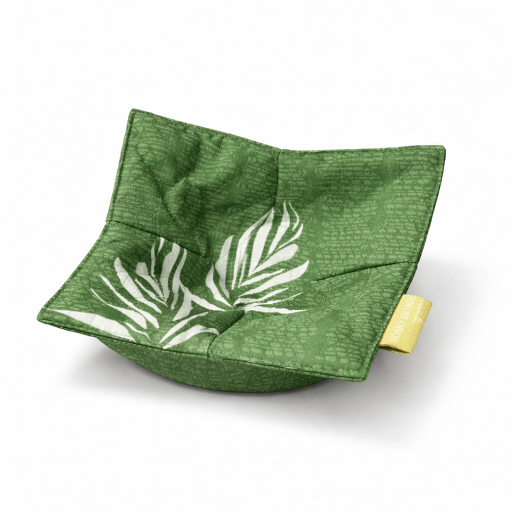 Green fabric bowl with leaf pattern on a white background