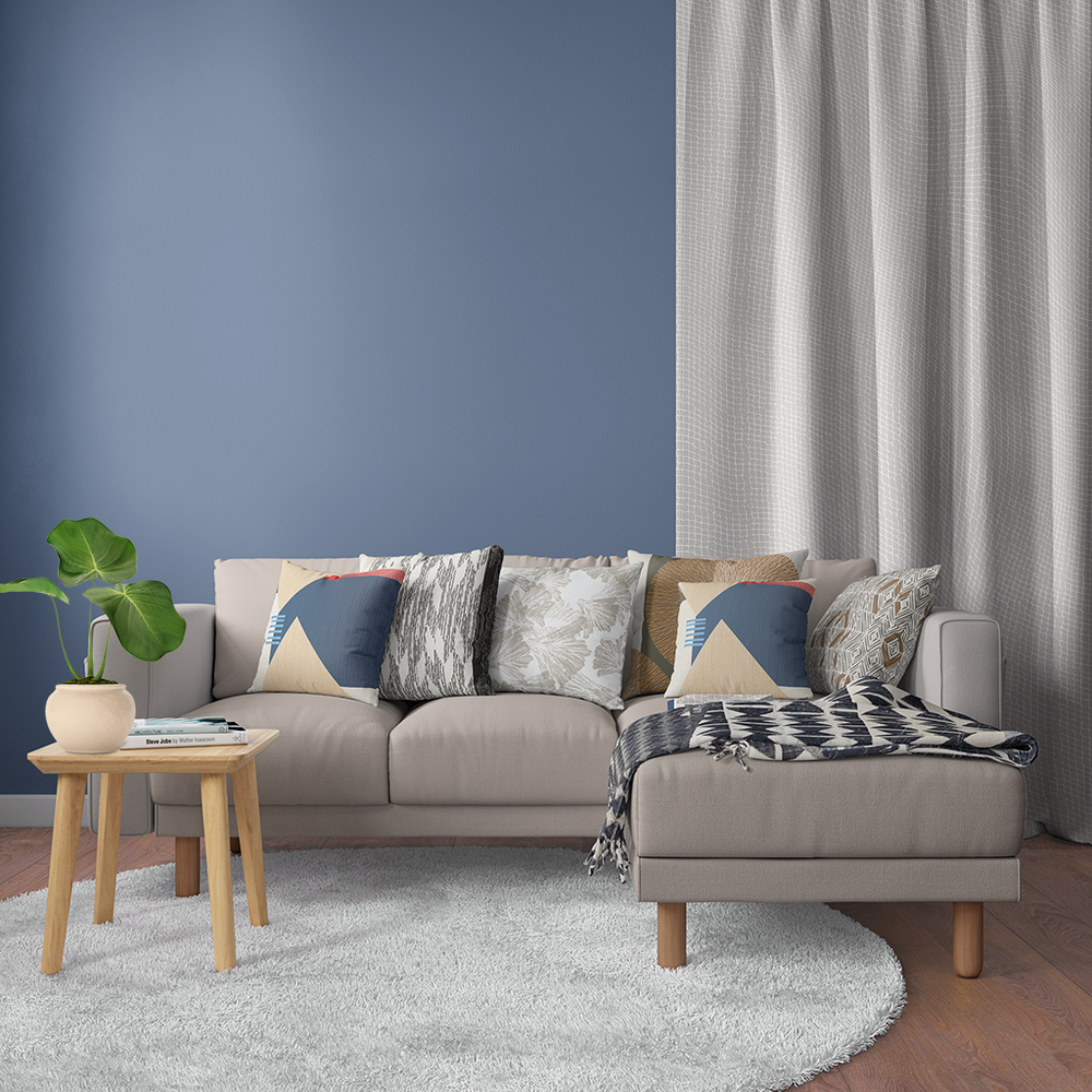 A chic living room with a blue wall and a grey couch in front of it, creating a stylish and modern ambiance, with a Black and Beige Kīpola Luxury as an accent piece.Throw