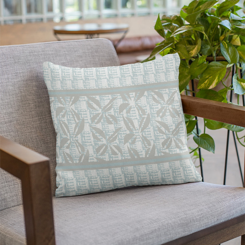 Pīʻāpā Square Pillowcase Sitting On a Grey Fabric Chair With Wooden Arms