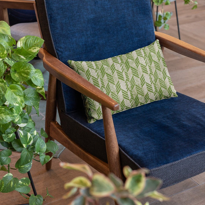 Sage and Ivory Kapa Hou Lumbar Pillowcase on a dark blue chair with plants on the side