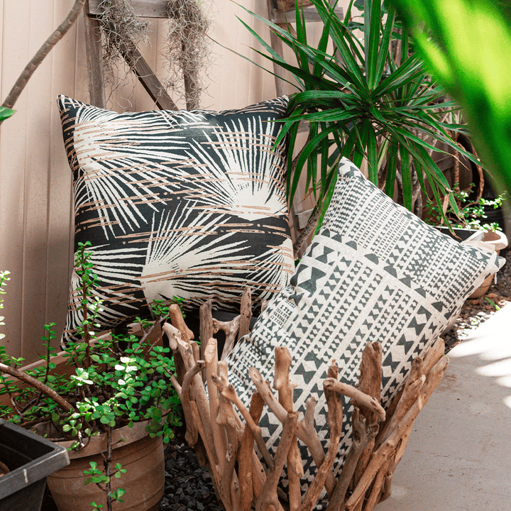 Black and Taupe Kāpili Lumbar Pillowcase and Dusk Loulu Square Pillowcase against a lush indoor garden