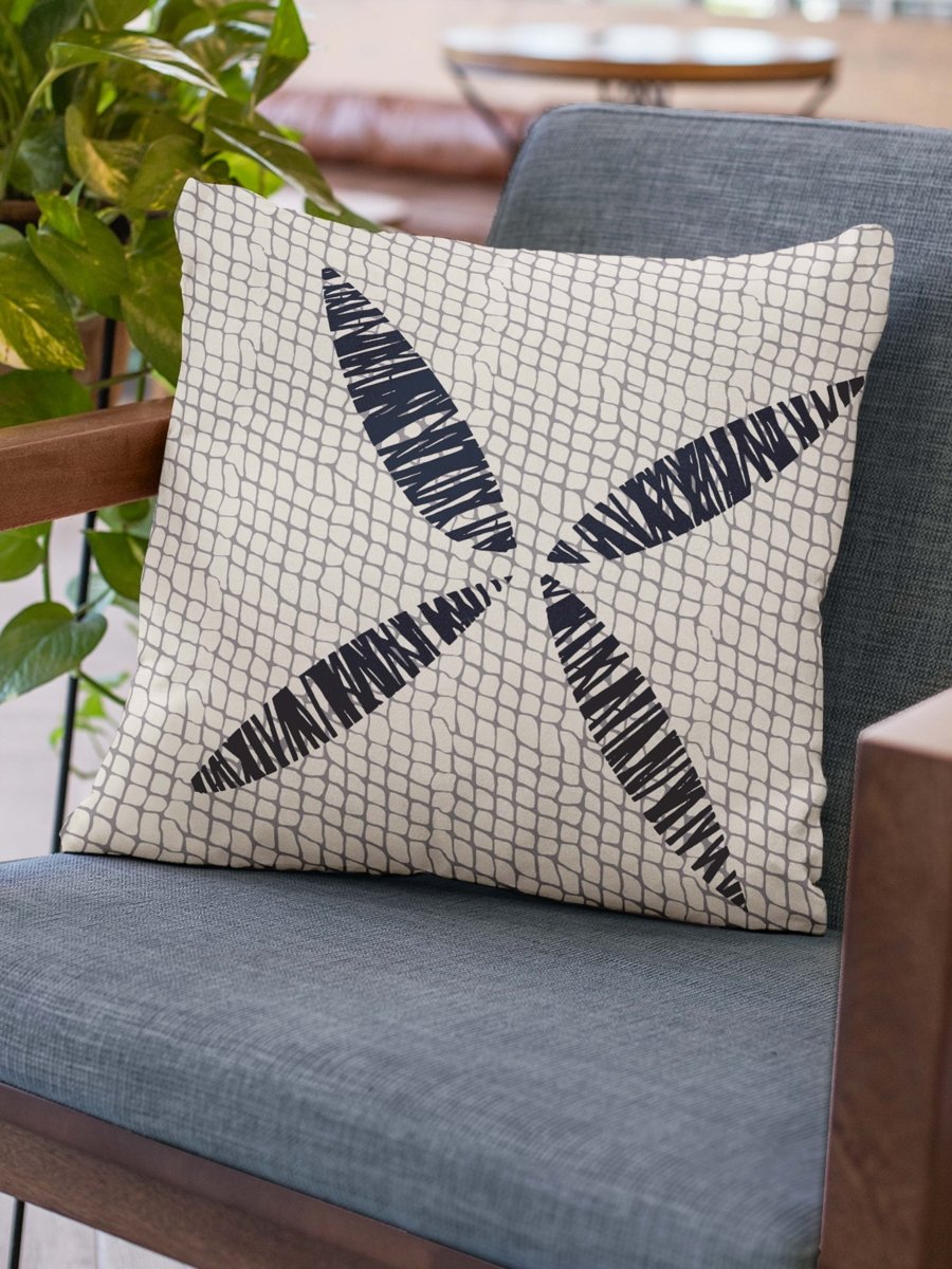 Midnight and Ivory Kapua Kai Square Pillowcase Set On a Blue Grey Chair With Wood Arms Next to a Plant
