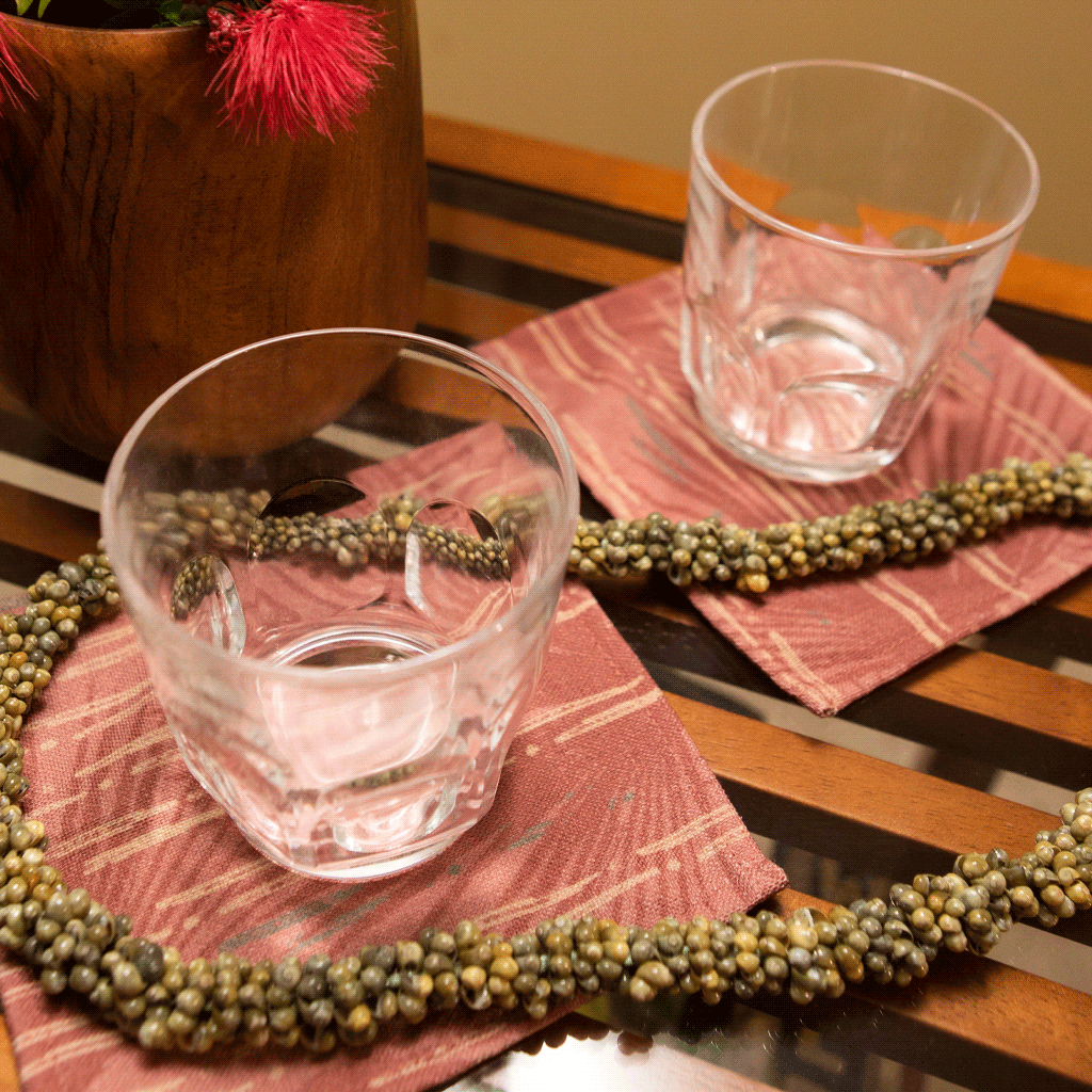 Red Loulu Cocktail Napkin Set under clear glasses and shell lei accent