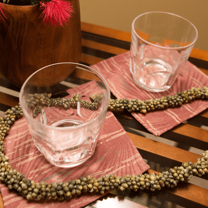 Red Loulu Cocktail Napkin Set under clear glasses and shell lei accent