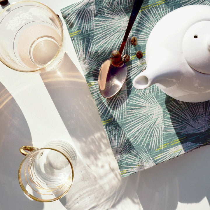 Teapot and spoon resting on Ivory and Blue Loulu Dining Napkin Set 