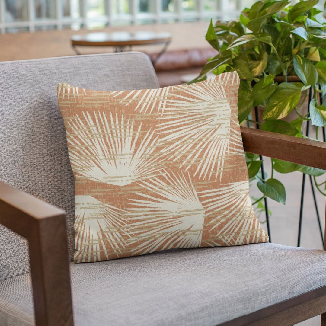 Sunset Loulu Square Pillow Sitting On a Grey Fabric Chair With Wood Arms