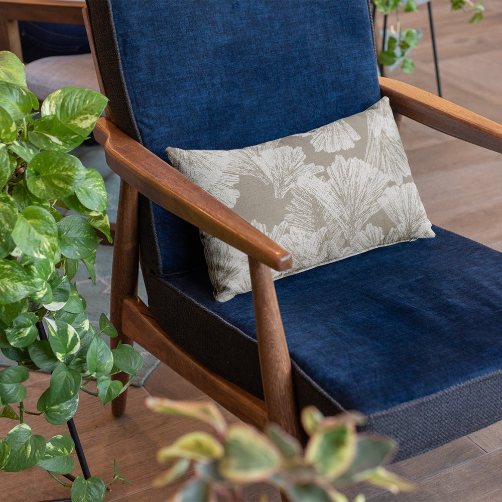 Ivory & Taupe Nahenahe Lumbar Pillowcase on a navy blue chair with plants on the side
