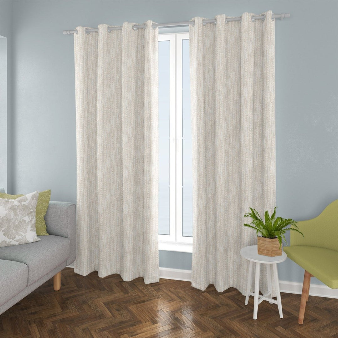 Niho Drapery Hawaii against a pale blue wall, with grey sofa and accent pillows as well as a little table and accent chair.