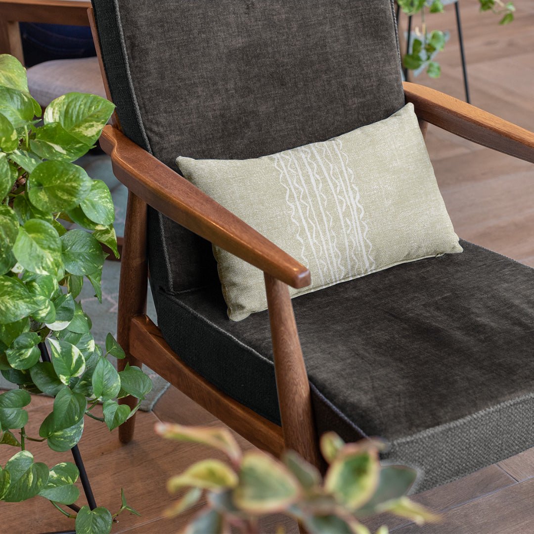 Ivory and Beige Niho Lumbar Pillowcase Sitting On a Dark Grey Fabric Chair with Wooden Arms