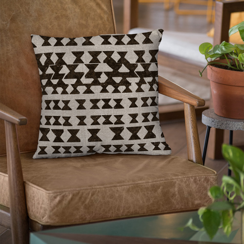 Black and Taupe Kāpili Square Pillowcase Placed On a Weathered Leather Chair